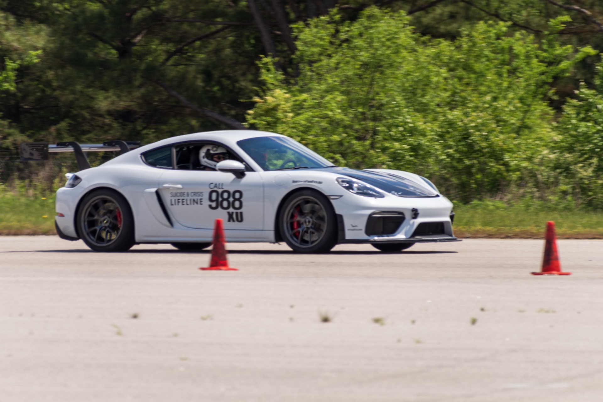 Drifting cornering shot of Team Wheelhouse Cayman GT4 988 between autocross cones