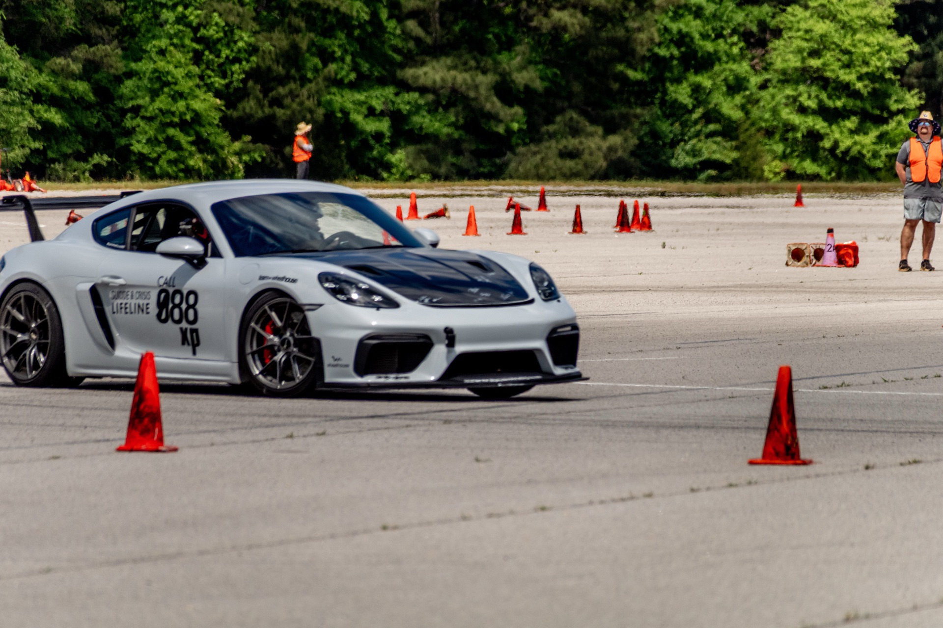 Front three-quarter of Cayman GT4 988 approaching the apex with course worker on grid