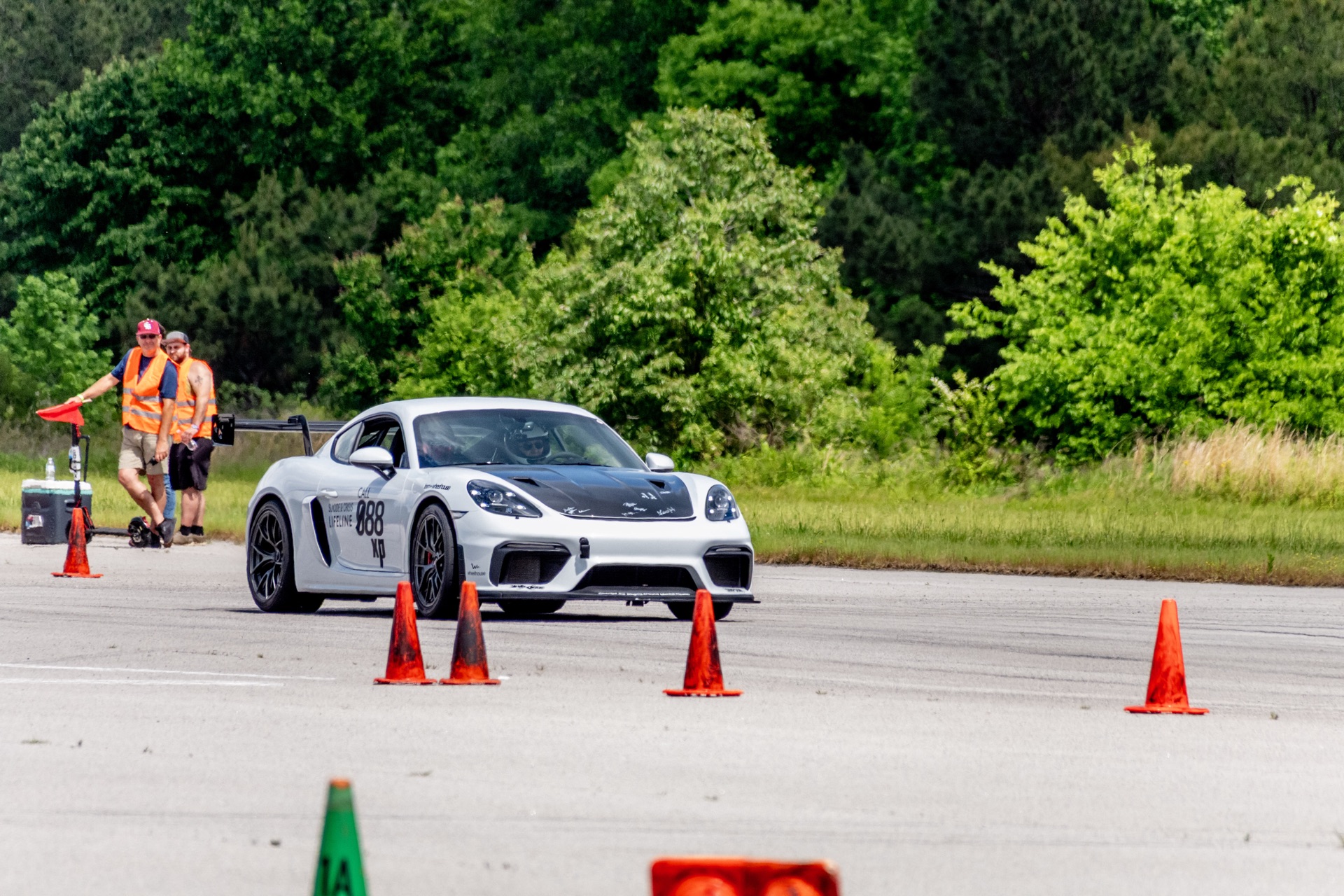 Cayman GT4 988 powering out of corner past SCCA course workers in orange