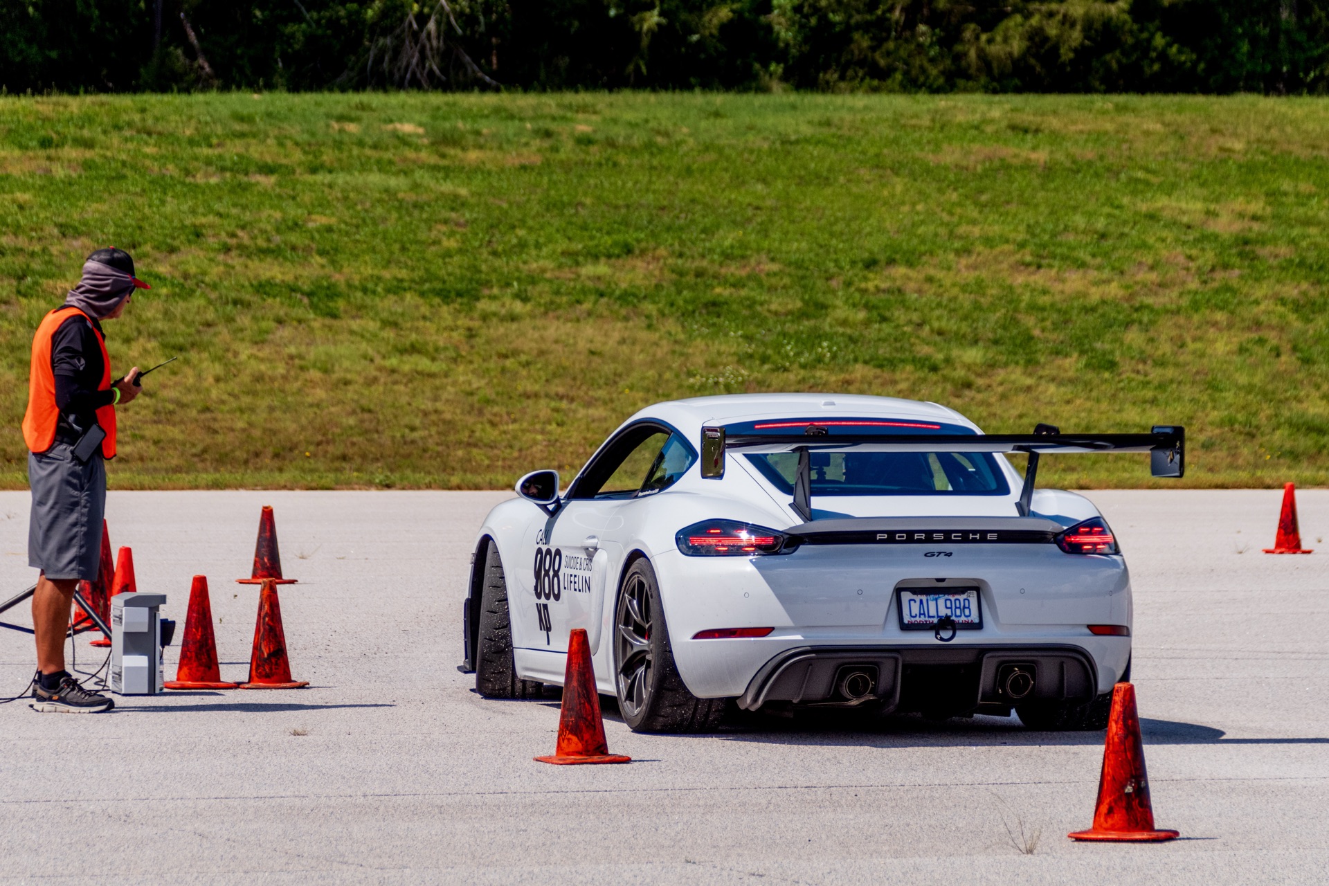 Rear of Team Wheelhouse Cayman GT4 988 at autocross start grid with course worker phoning run times