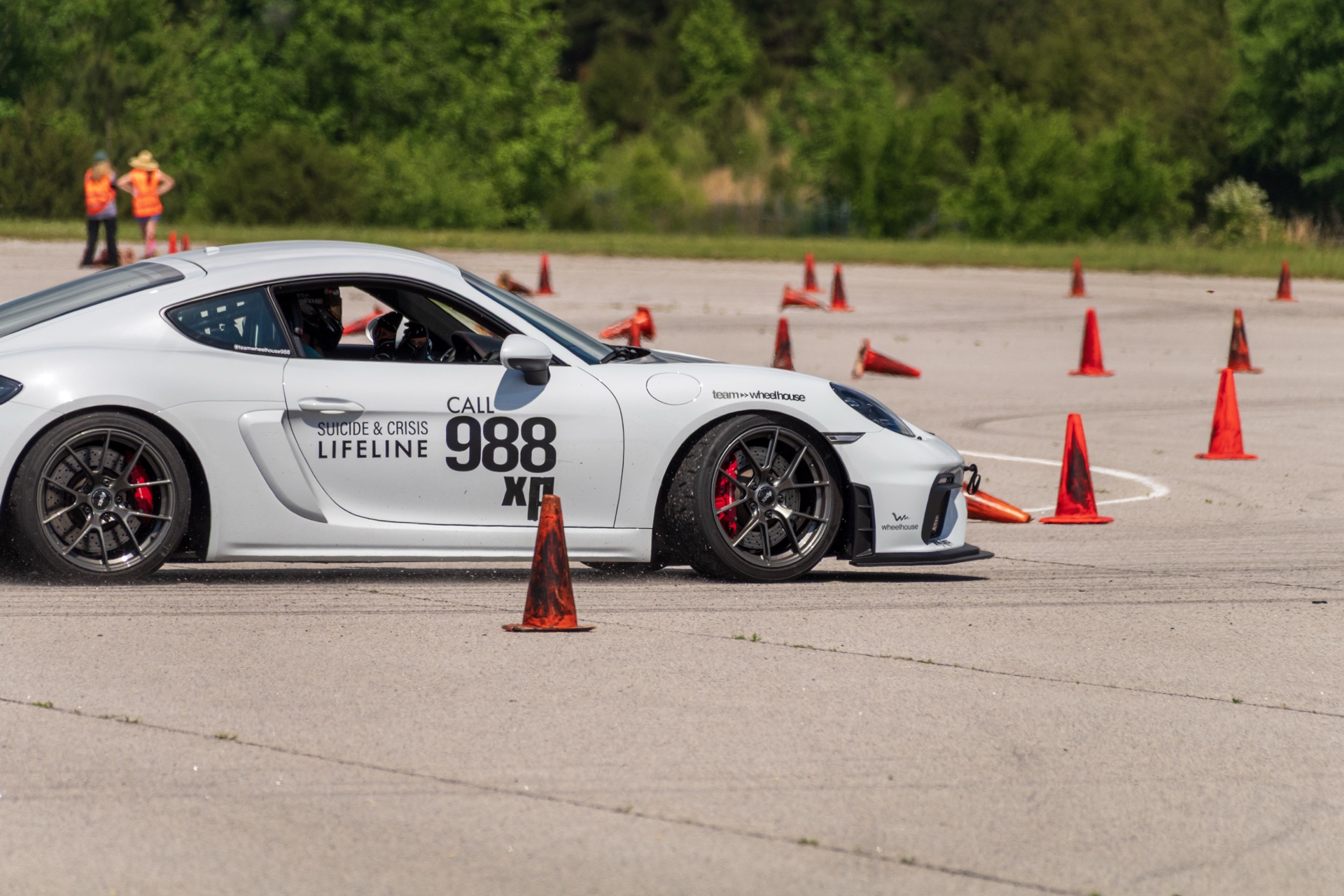 Front three-quarter of Cayman GT4 988 mid-corner with SCCA course workers in background