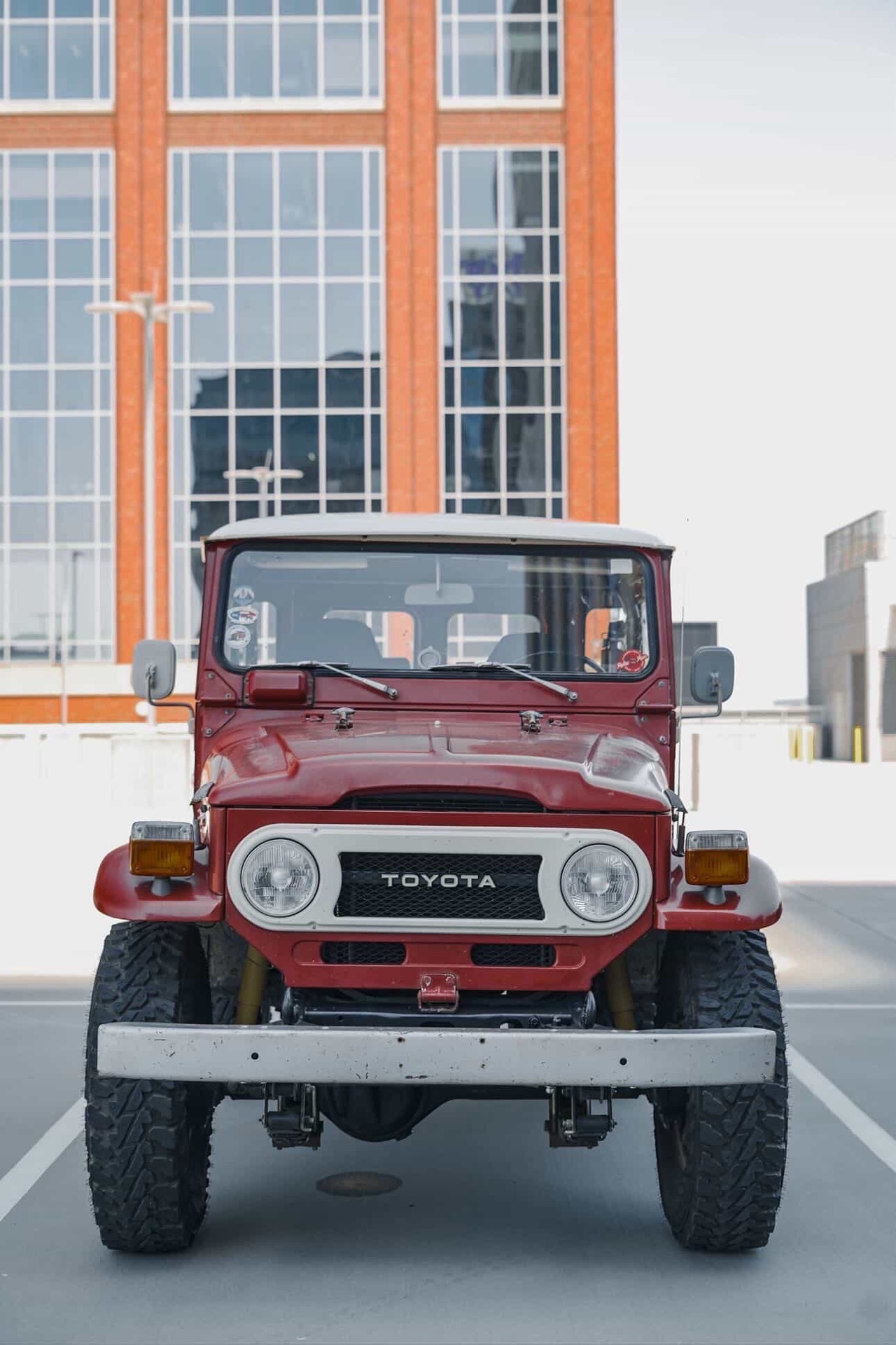 Vintage red Toyota Land Cruiser FJ40 head-on with downtown Charlotte tower behind it