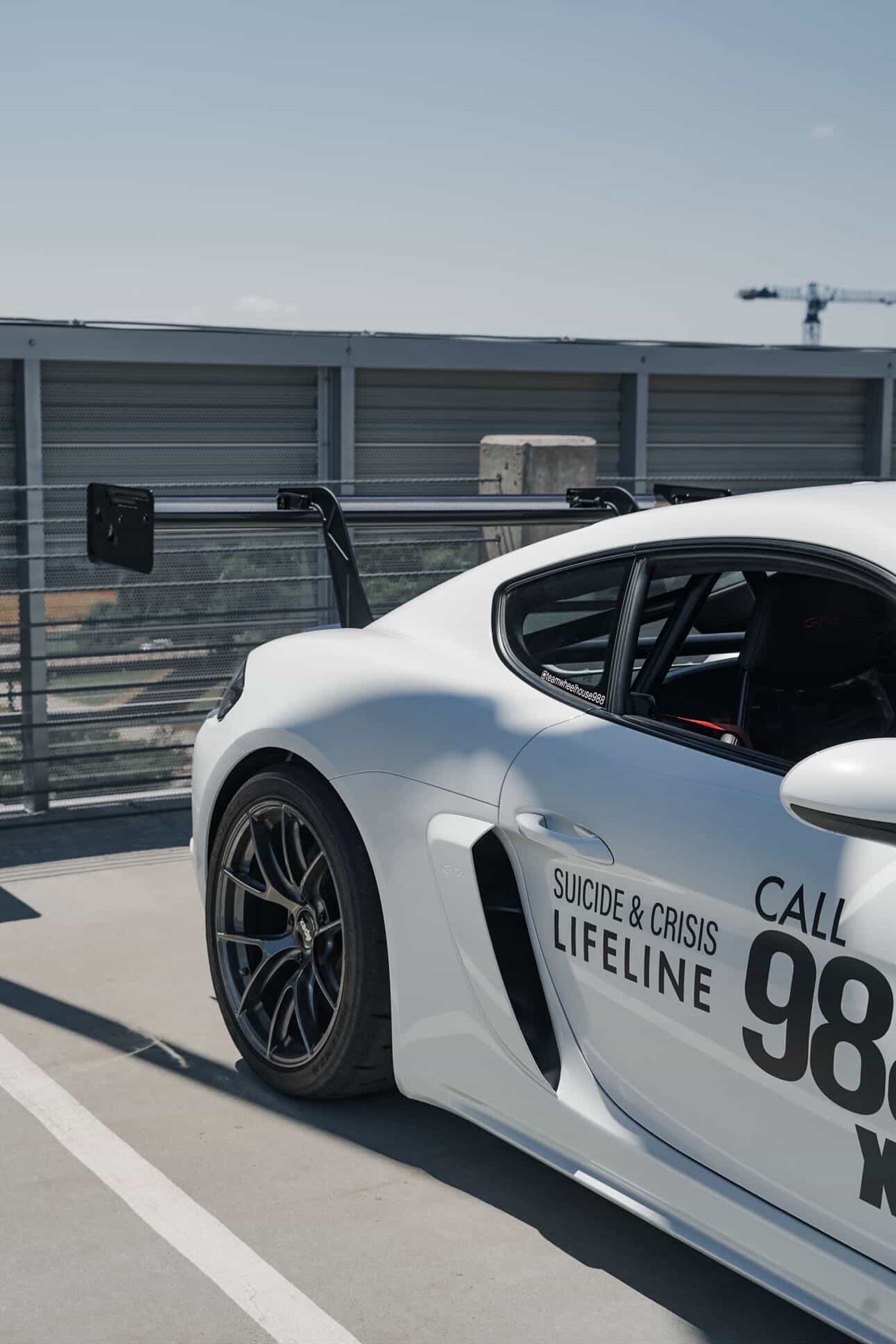 Rear quarter of the Team Wheelhouse Cayman GT4 showing the Suicide and Crisis Lifeline Call 988 livery